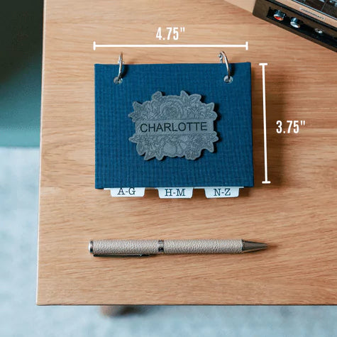 Address book with writing pen for scale. Book measures 4.75" wide and 3.75" tall.