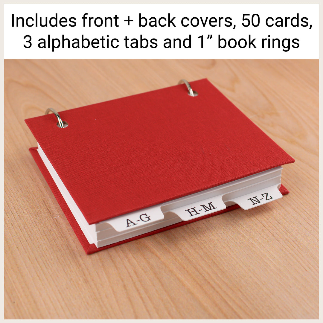 Red password book with tabs, shown with text listing the included covers, 50 cards, three alphabetical dividers, and 1-inch rings.