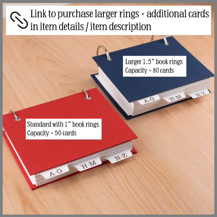 Two address books - one red and one blue, with text indicating ring size and capacity on a wooden surface.