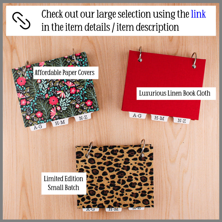 Three address books with different designs on a wooden surface, labeled 'Affordable Paper Covers', 'Luxurious Linen Book Cloth', and 'Limited Edition Small Batch'.