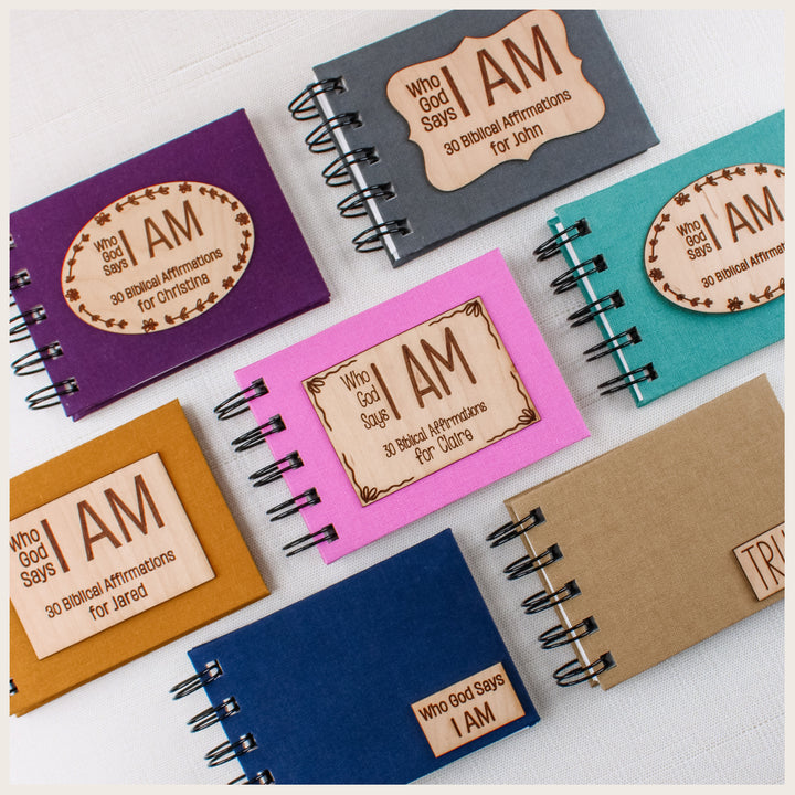 Seven Christian affirmation books in assorted book cloth colors, showing small title plaques and larger personalized wood plaque designs.