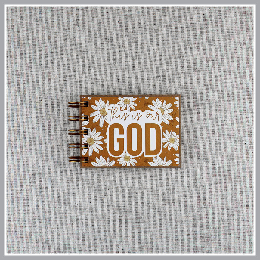 Small spiral bound attributes of God book in Daisy style with yellow background and ivory flowers. Front cover says "this is our GOD".