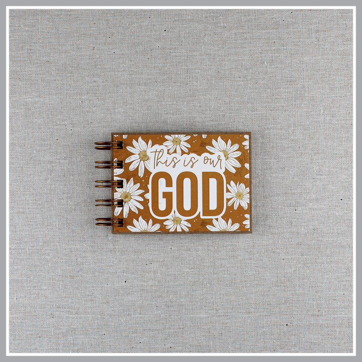 Small spiral bound attributes of God book in Daisy style with yellow background and ivory flowers. Front cover says "this is our GOD".