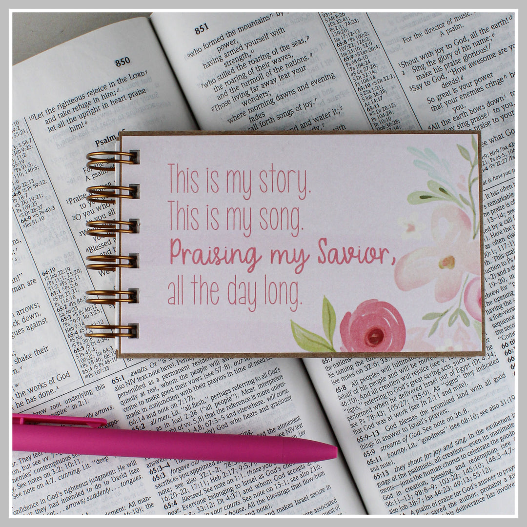 Pink Floral Christian journal resting on an open Bible for prayer, gratitude and daily quiet time.
