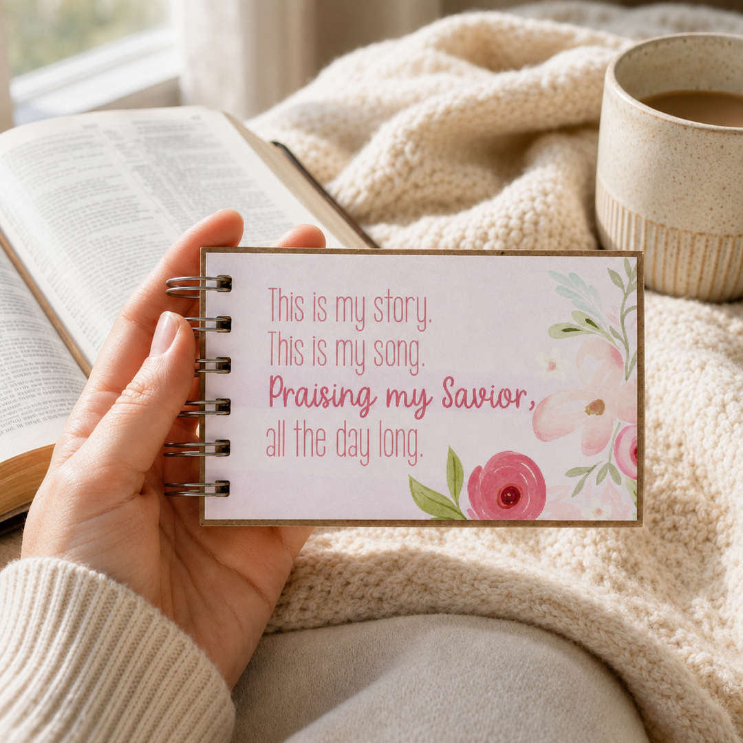 Pink floral Christian prayer journal held in hand beside a Bible and coffee.