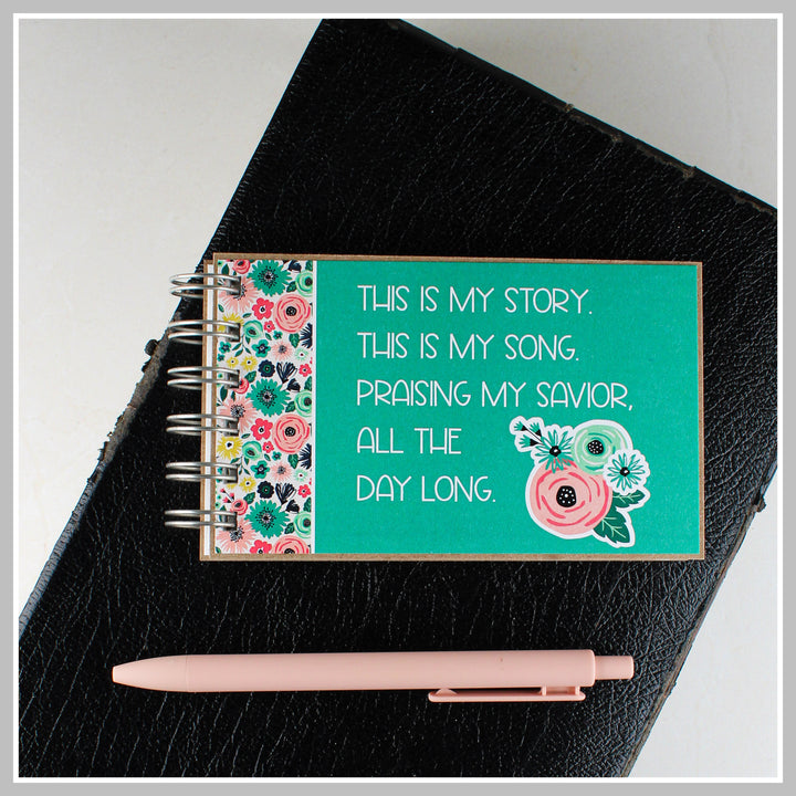 Teal Christian journal resting on a Bible for prayer, gratitude and daily quiet time.