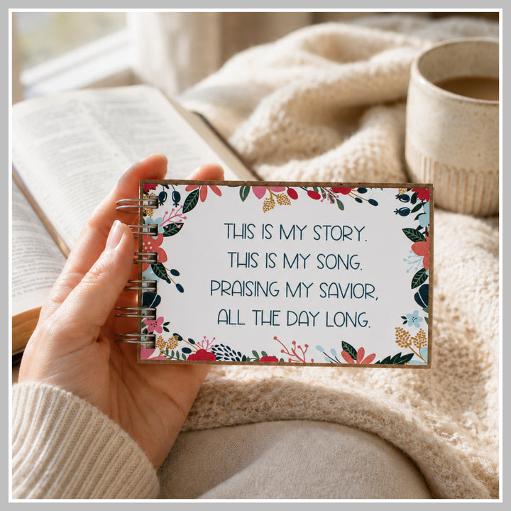 Flower frame Christian prayer journal held in hand beside a Bible and coffee.