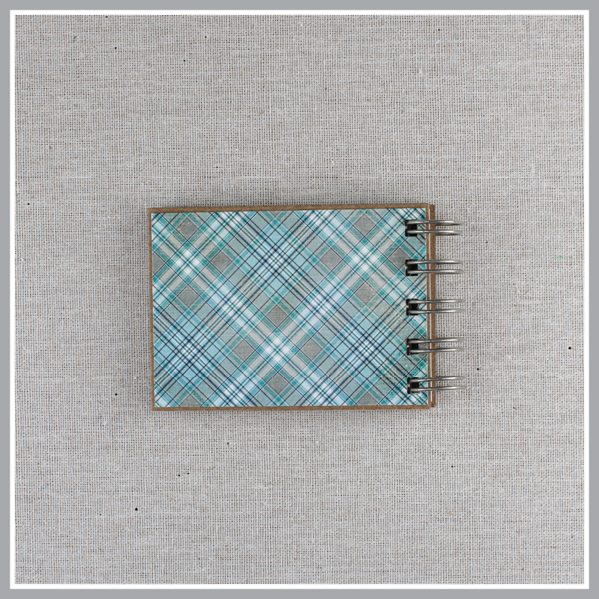 Back cover of spiral-bound book with 'This is our God' text on a plaid blue and gray cover.