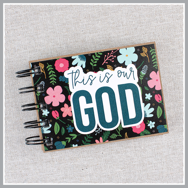 Front cover close up of God's attributes book with black background and pastel florals. Text says 'this is our GOD'.