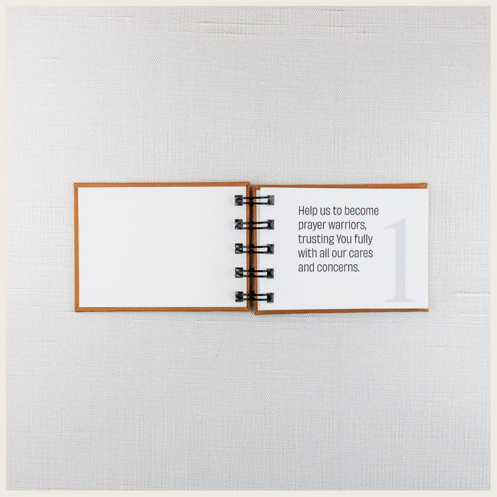Family prayer book open to prayer 1, asking God to help us become prayer warriors and trust Him with our cares and concerns.