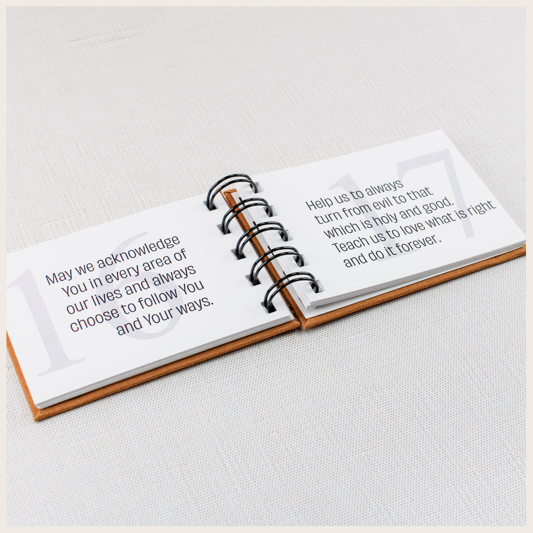 Open family prayer book showing prayers 16 and 17 about following God and choosing what is holy and good.