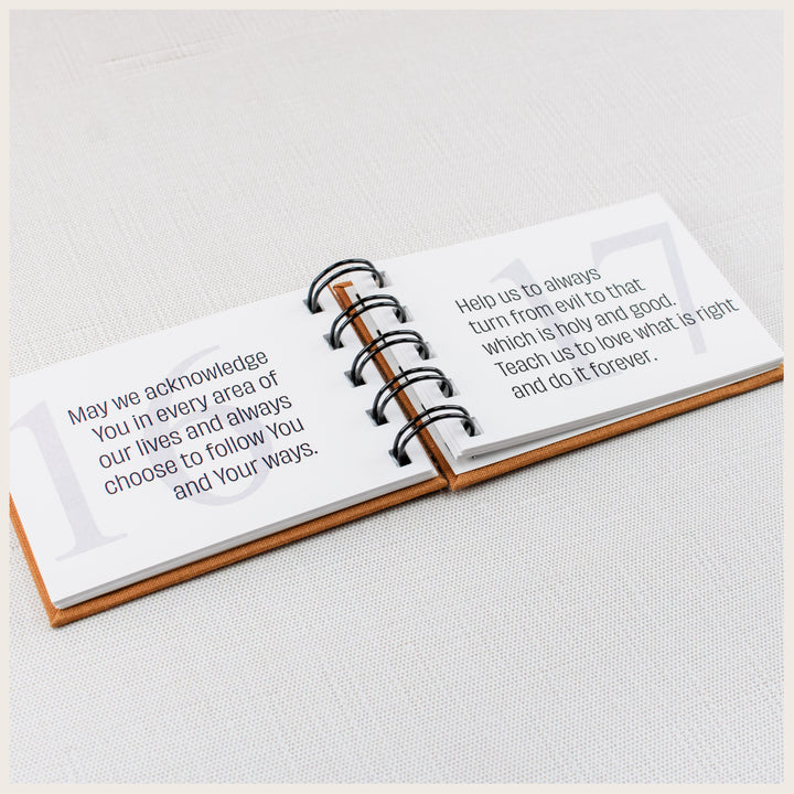 Open family prayer book showing prayers 16 and 17 about following God and choosing what is holy and good.