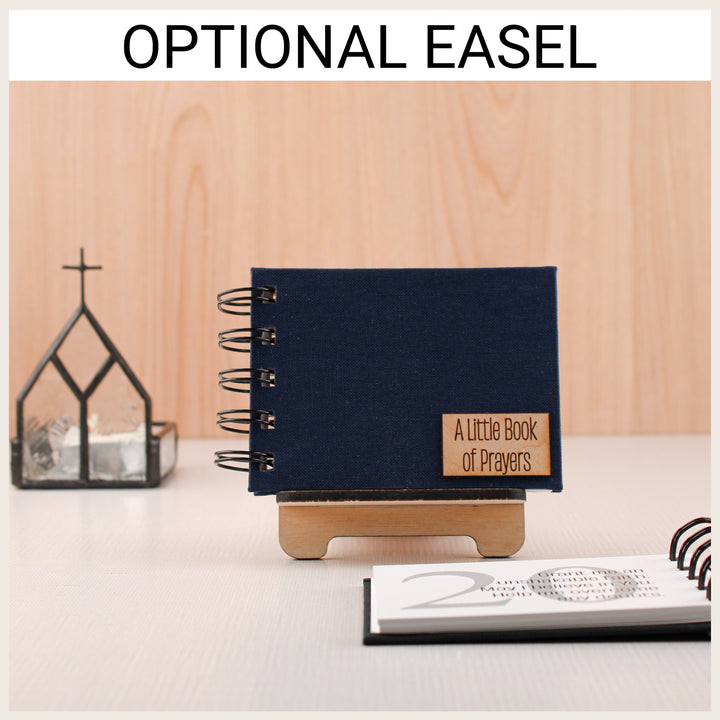 Navy prayer book with an A Little Book of Prayers plaque displayed on an optional wooden easel, with an open prayer book in front.