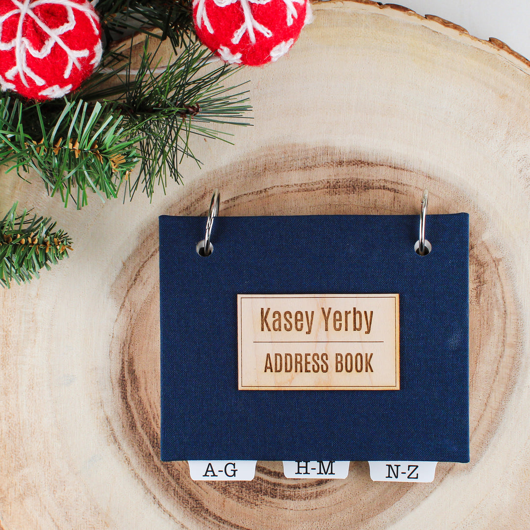 personalized address book with navy blue book cloth covers and a personalized wood veneer nameplate on front cover.