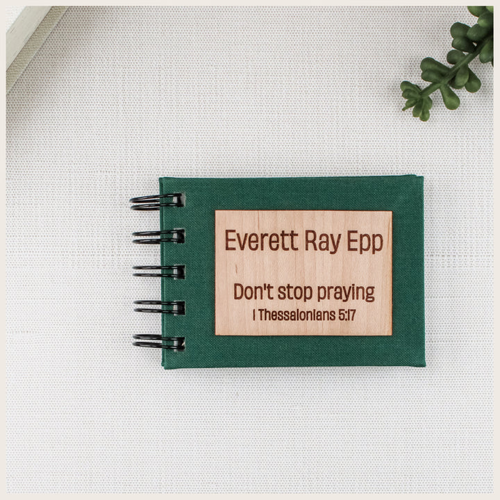 Forest green spiral prayer book with a wood plaque engraved Everett Ray Epp, Don’t stop praying, and 1 Thessalonians 5:17.