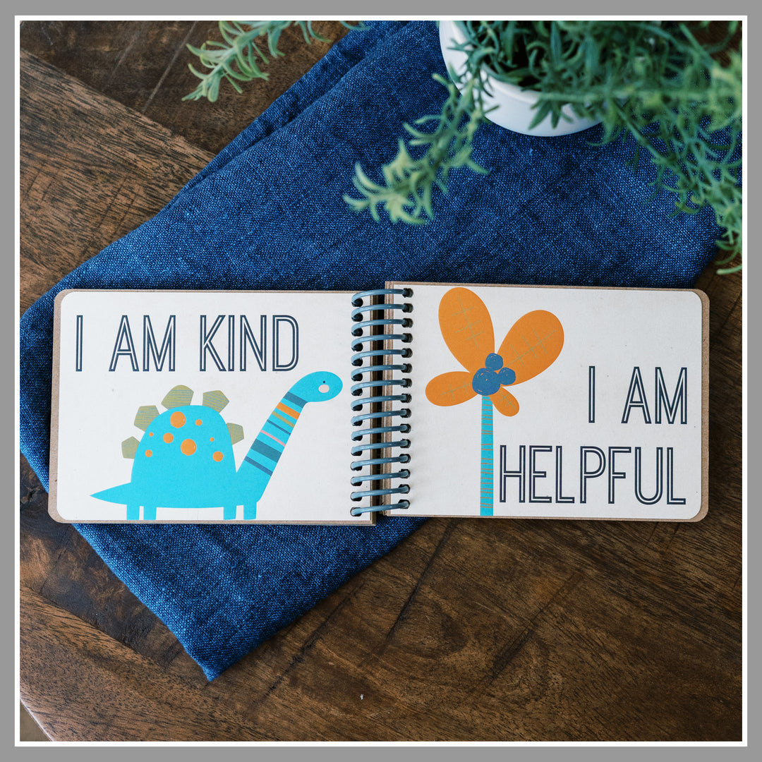 Open Dinosaur affirmation book showing “I am kind” and “I am helpful” pages with colorful dinosaurs.
