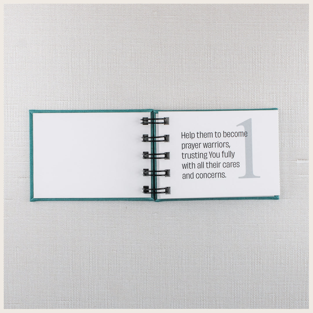 Open teal prayer book showing prayer 1, asking God to help loved ones become prayer warriors and trust Him with their concerns.