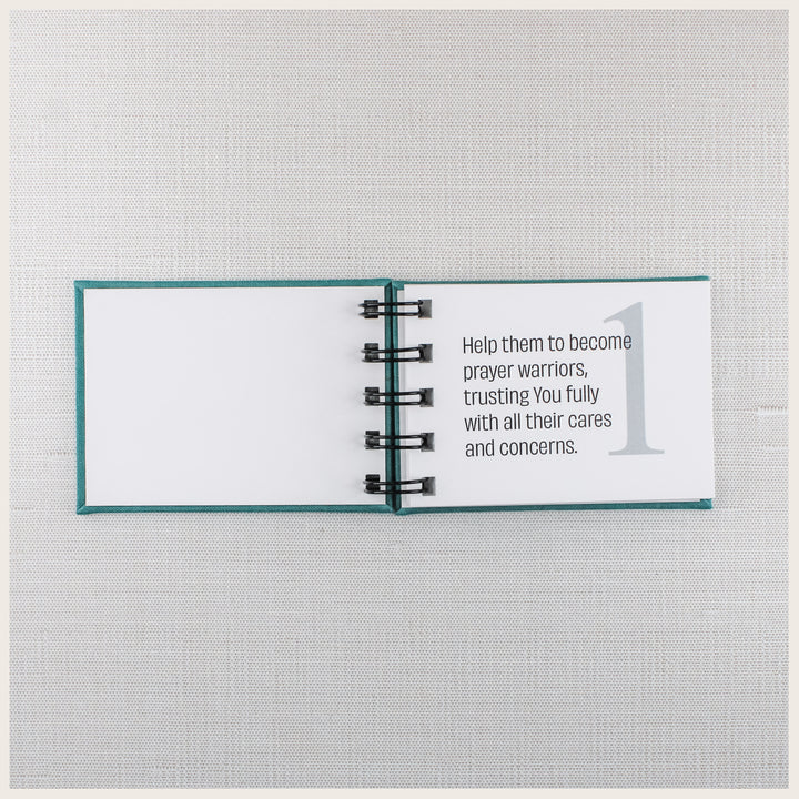 Open teal prayer book showing prayer 1, asking God to help loved ones become prayer warriors and trust Him with their concerns.
