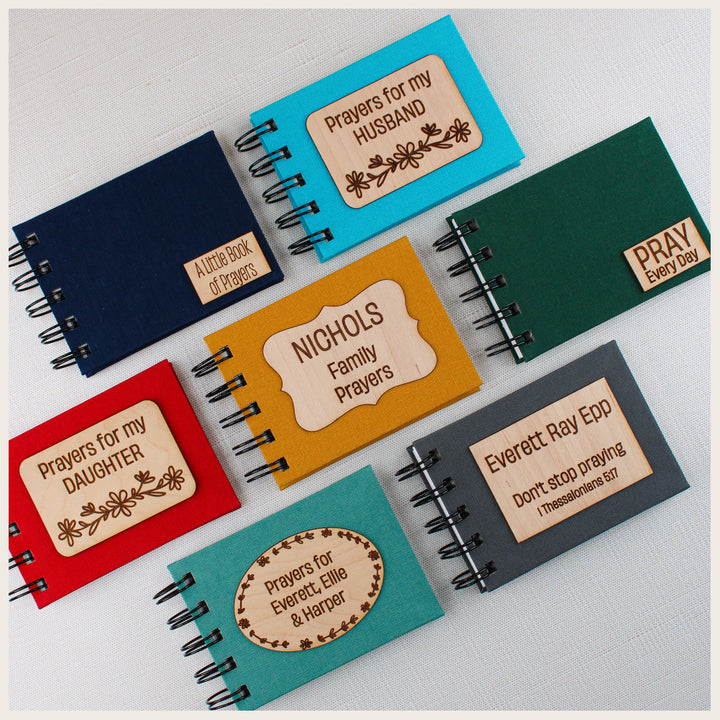 Seven spiral prayer books in assorted book cloth colors with standard and custom wood plaques for personal prayer, family, husband, daughter and children.