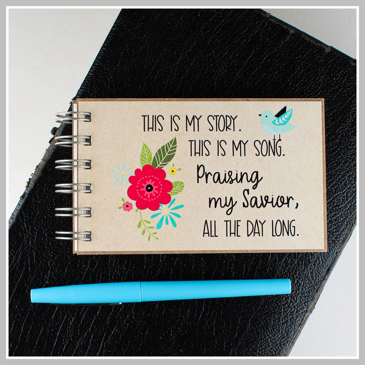 Bluebird Christian journal resting on a Bible for prayer, gratitude and daily quiet time.
