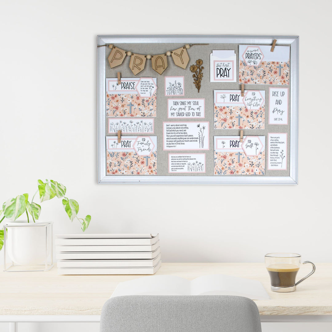 Pink prayer board on the wall above a desk.
