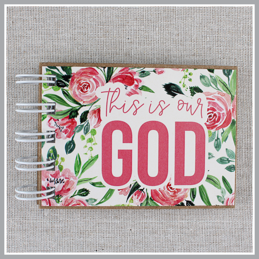Close up of cover of attributes of God spiral bound book with pink flowers and green leaves. Front cover says "this is our GOD".