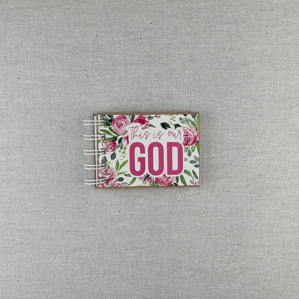 Video of attributes of God spiral bound book with pink flowers and green leaves. Front cover says "this is our GOD".
