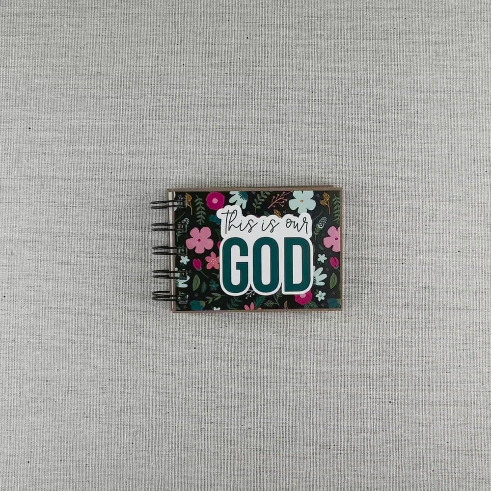Video of God's attributes book with black background and pastel florals. Text says 'this is our GOD'. Book includes 30 attributes of God along with a short description and corresponding Bible verse.