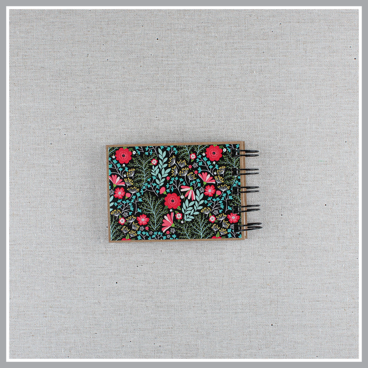 Back cover of God's attribute book with a black background and bright florals. The cover of this small, spiral-bound book says "this is our GOD".