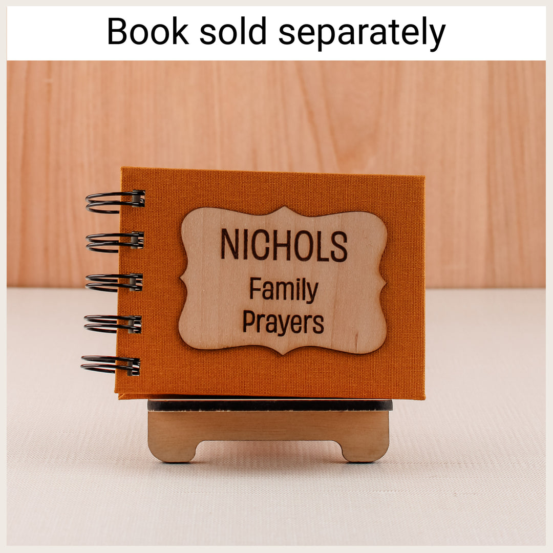 Wood easel holding a gold personalized Nichols Family Prayers spiral book. Book sold separately.