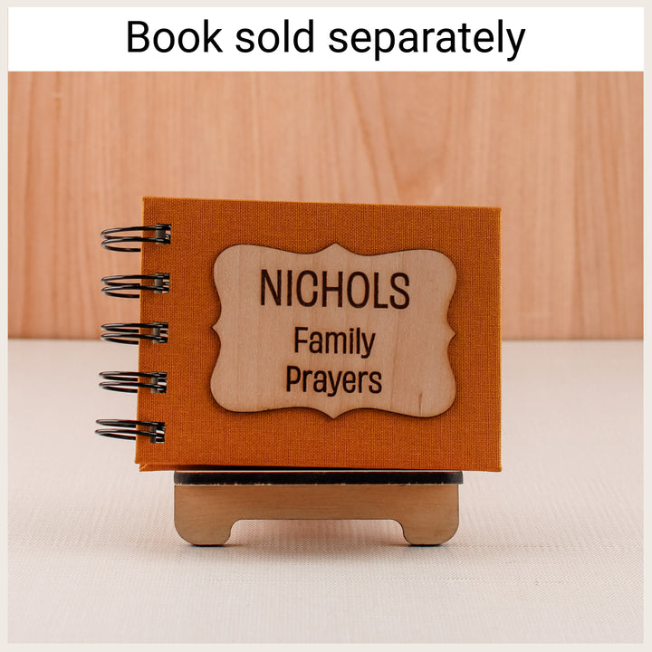 Wood easel holding a gold personalized Nichols Family Prayers spiral book. Book sold separately.