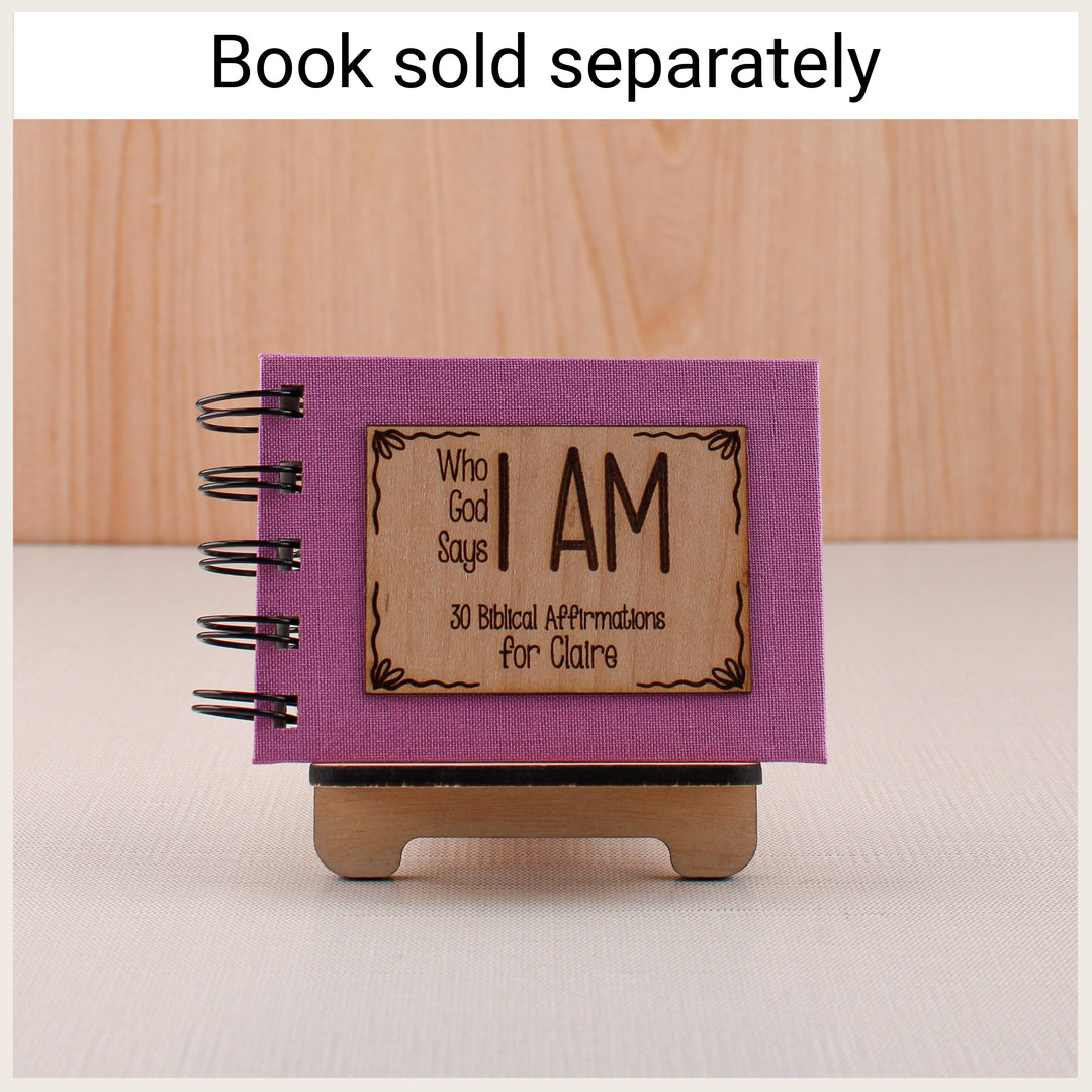 Wood easel displaying a purple personalized Who God Says I Am affirmation book. Book sold separately